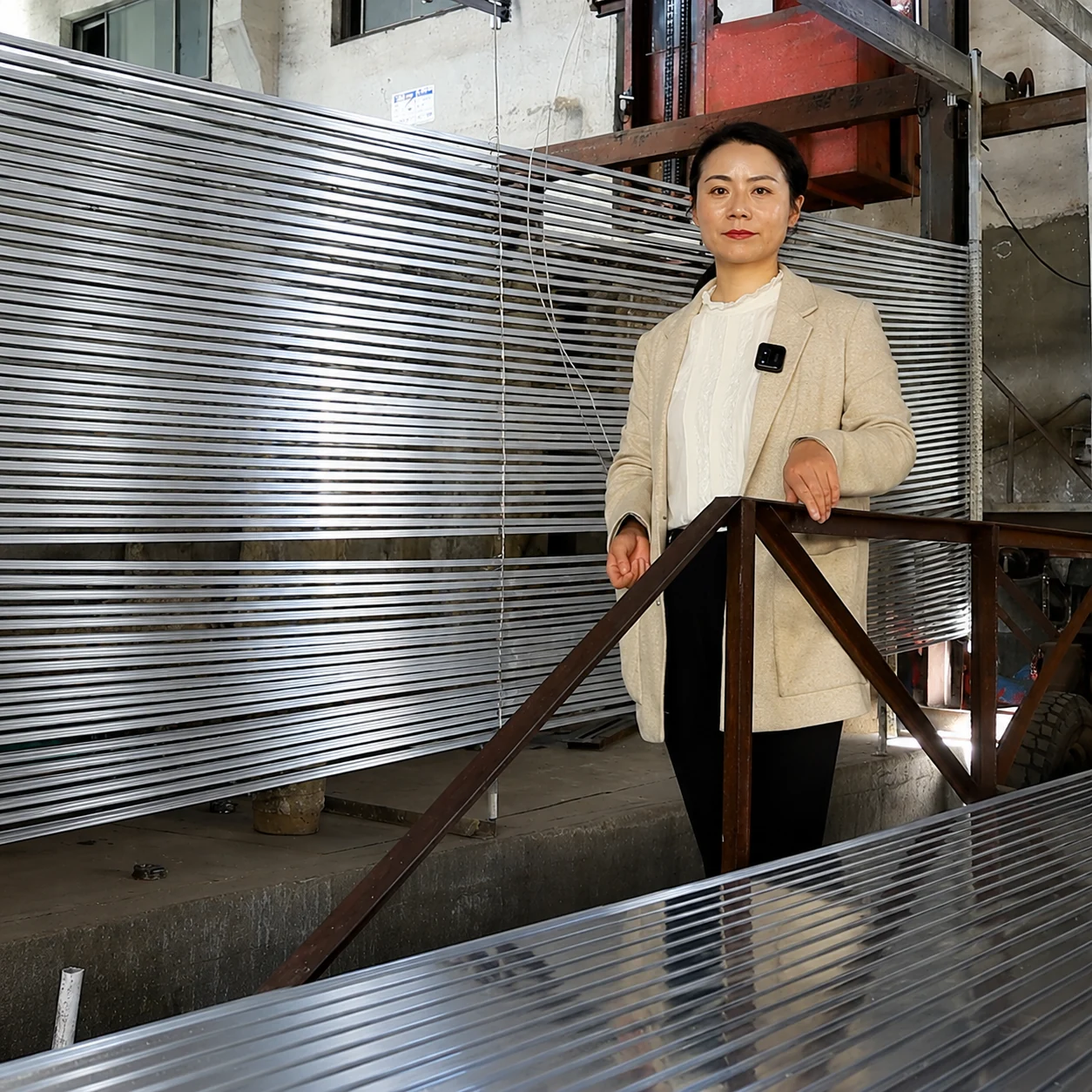 A FEIYANG team member beside curtain-track profiles in the workshop